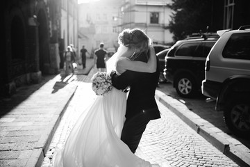 Groom whirls elegant bride on stone road