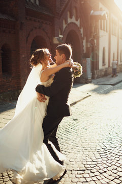Bright evening sun shines over wedding couple whirling on the street