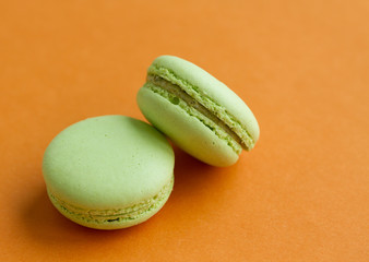 Pair of Green pistachio macaroons over orange background