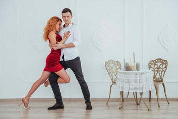 Young beautiful woman in a red dress and a man dancing, isolated on a white background.