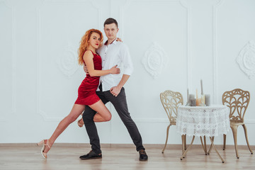 Young beautiful woman in a red dress and a man dancing, isolated on a white background.