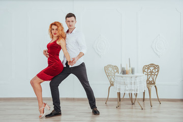 Young beautiful woman in a red dress and a man dancing, isolated on a white background.