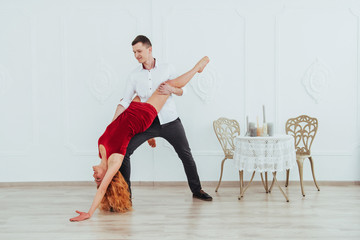 Young beautiful woman in a red dress and a man dancing, isolated on a white background.