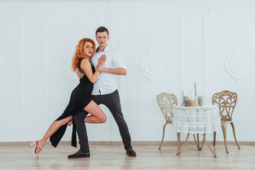 Young beautiful woman in a black dress and a man in white shirt dancing.
