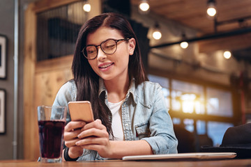 Delighted female person looking at her phone