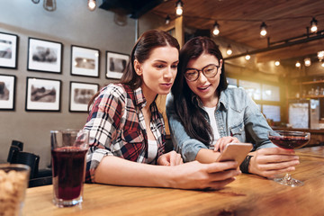 Cute happy females looking at phone