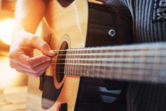 Guitarist plays guitar on wooden background, close up