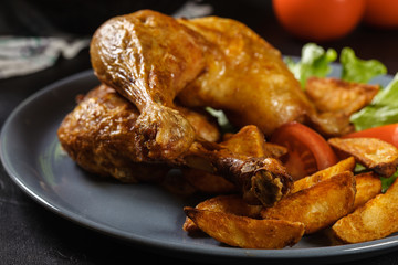 Roasted chicken legs with potato wedges and tomatoes