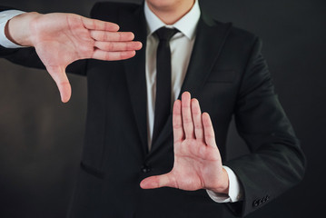 The young businessman in a suit shows his hand on a dark background isolated