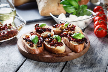 Appetizer bruschetta with sun-dried tomatoes, olives and mozarella.