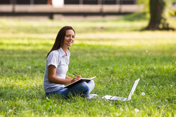 Beautiful businesswoman is sitting at the park and working.