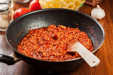 Minced meat fried in tomato sauce in the frying pan. Preparation cannelloni