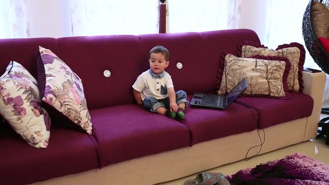 A little boy is sitting on the couch and watching TV