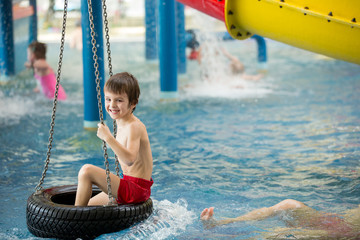 Sweet child, boy, playing in water world playground, enjoying attractions