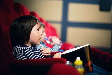 Two preschool children, twin brothers, watching movie in the cinema
