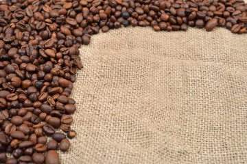 Vintage photo, roasted coffee beans on brown jute background. Morning pleasure. Still life. Selective focus. Copy space