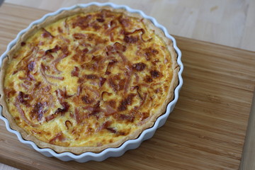 Quiche Lorraine in white dish on brown chopping board