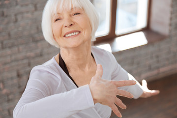 Cheerful elderly woman mastering dance skills at the lesson