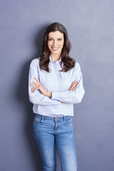 Smiling beauty. Shot of a beautiful casual woman looking at camera and smiling while standing against a grey wall.