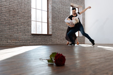 Mature dance instructor tangoing with aged woman at the ballroom