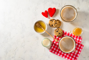 Obraz na płótnie Canvas Healthy breakfast. Light background with red napkin. Coffee, soy milk, peach juice and cookies with chocolate chips. Two hearts.