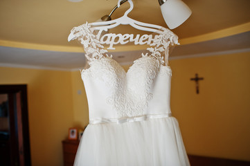 White wedding dress at hangers on the chandelier at ceiling.