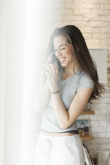 Morning scene. Woman using cell phone next to window