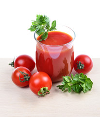 glass full of freshly prepared tomato juice on wooden board against white background.