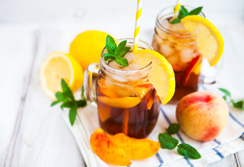 Homemade lemonade with ripe  peaches and fresh mint. Fresh peach ice tea on white wood table. Copy space background.