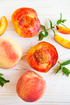 Fresh peaches with mint on wooden white background. Top view, flat lay.