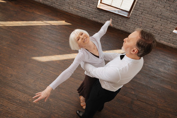 Optimistic retired dance couple enjoying waltz in the dance studio