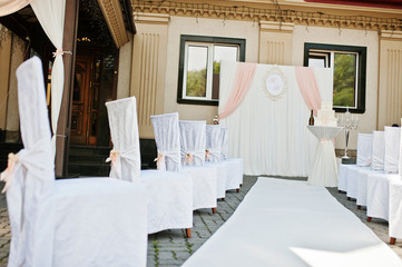 Wedding chairs with pink bows on site wedding ceremony.