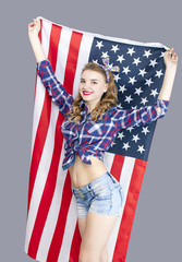 
Attractive young woman  stand with American  flag  and smile, looking direct
