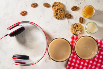 Healthy breakfast. Light background with red napkin. Coffee, soy milk, peach juice and cookies with chocolate chips. Headphones.