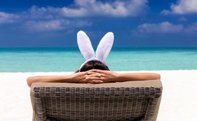 Frau mit Hasenohren auf Liegestuhl am tropischen Strand