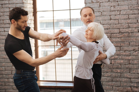 Talented dance instructor teaching aging couple at the ballroom