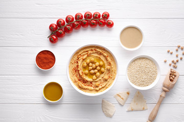 Homemade hummus traditional rustic healthy vegan dip chickpeas paste snack flat lay with natural ingridients, tahini, paprika, olive oil, pitta on table. Healthy vegetarian diet nutrition protein food