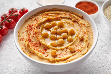 Hummus close up with ingridients, healthy diet natural vegetarian snack protein food. Traditional mediterranean appetizer. Sesame, paprika, tahini, pita bread and olive oil on white table