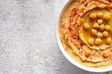 Hummus close up with paprika, tahini, and olive oil, healthy diet natural vegetarian snack protein food. Traditional mediterranean appetizer on white table