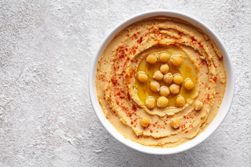 Hummus traditional middle eastern dip paste close up with paprika, tahini, and olive oil, healthy diet natural vegetarian snack protein food. Traditional mediterranean appetizer on white table
