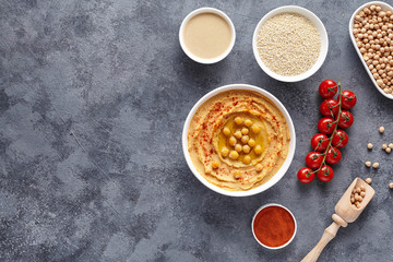 Hummus homemade middle eastern dip paste flat lay with paprika, tahini, sesame, and olive oil, healthy diet natural vegetarian snack protein food. Traditional mediterranean appetizer on blue table