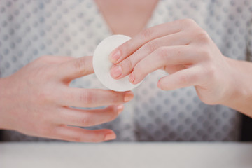 Woman is cleaning nail polish with the cotton pad