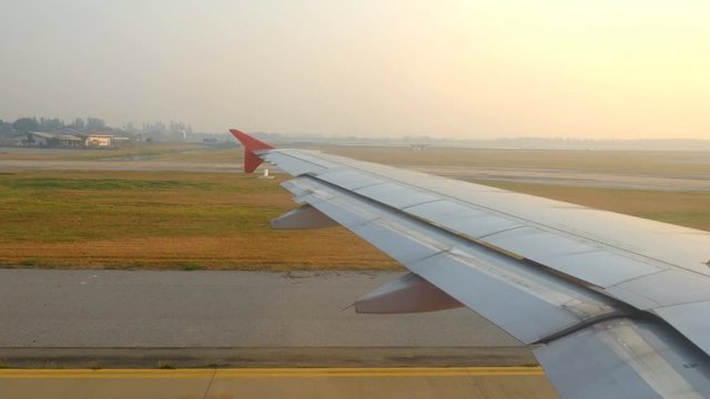 Airplane taxiing on runway at airport in morning, view through from window