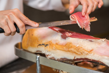 Chef slices serrano ham.
