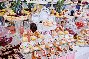 Wedding reception table with different fruits, cakes and sweets.