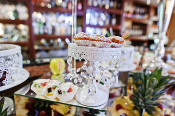 Wedding reception table with different fruits, cakes and sweets.