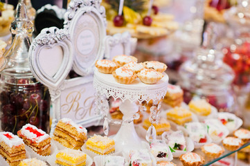 Wedding reception table with different fruits, cakes and sweets.