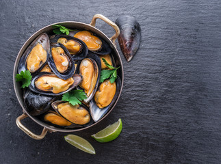 Mussels in copper pan on the graphite background.