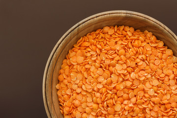 Red lentils in a pottery top view. Background with texture of grains of lentils. Orange bright food background top view.