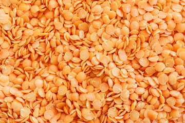 Red lentils. Background with texture of grains of lentils. Orange bright food background top view.